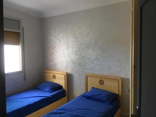 duas camas num quarto com lençóis azuis e uma janela em Appartement Plage & Famille em Ras El Ma