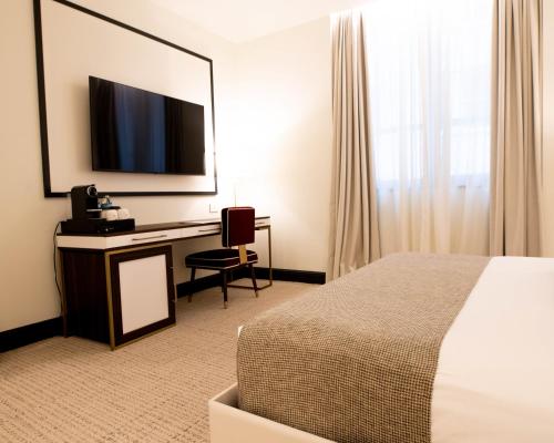 a hotel room with a bed and a desk with a television at Dylan Hotel NYC in New York