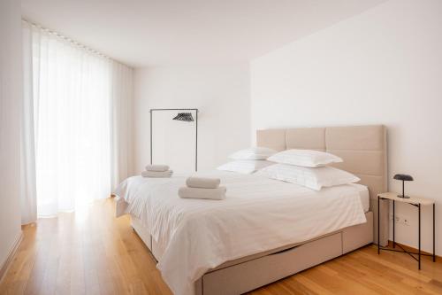 a white bedroom with a large bed with white sheets and pillows at Adriatic Queen Residence in Split