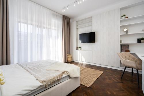 ein Schlafzimmer mit einem Bett, einem TV und einem Stuhl in der Unterkunft Three Bedrooms Apartment in Bukarest