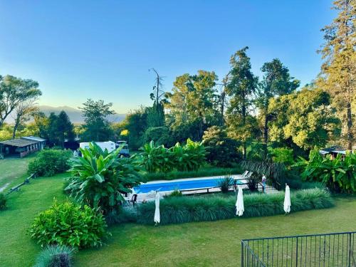 un jardín con sombrillas y una piscina en El Portal de Cerrillos, Hostería de Campo en Cerrillos