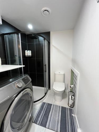 a bathroom with a washing machine and a toilet at Luxueuse Villa, Unique en ville in Drummondville