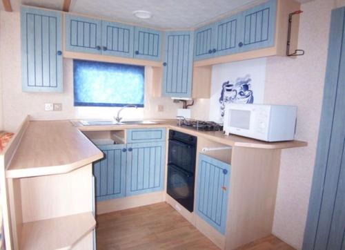 a small kitchen with blue cabinets and a microwave at Mobilhome Vieux Boucau les bains in Vieux-Boucau-les-Bains