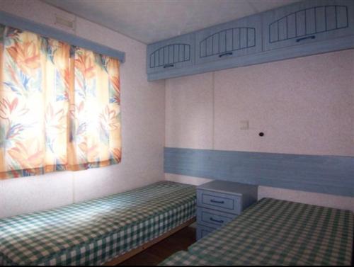 a bedroom with two twin beds and a window at Mobilhome Vieux Boucau les bains in Vieux-Boucau-les-Bains
