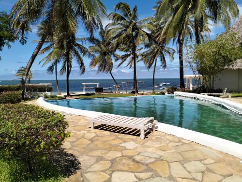 een zwembad met palmbomen en de oceaan bij MARIA the Star on the Sea Beach cottages, cottage Mama in Malindi