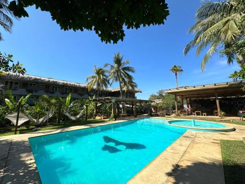 a swimming pool in a resort with palm trees at Straw Hat Surf Hostel & Bar in Brisas de Zicatela