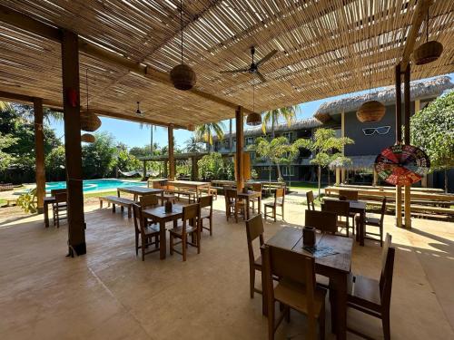a restaurant with tables and chairs and a pool at Straw Hat Surf Hostel & Bar in Brisas de Zicatela
