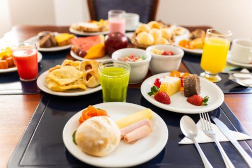 a table topped with plates of breakfast foods and drinks at Wynn Batel in Curitiba