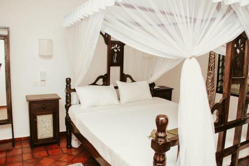 een slaapkamer met een hemelbed bij MARIA the Star on the Sea Beach cottages, cottage Mama in Malindi