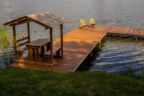 a wooden dock with two chairs and a table on the water at Na Dubie in Zalewo