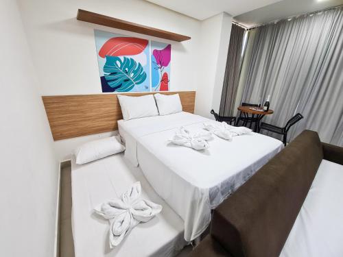 a hotel room with two beds with white sheets at Porto Star Prime By AFT in Porto De Galinhas