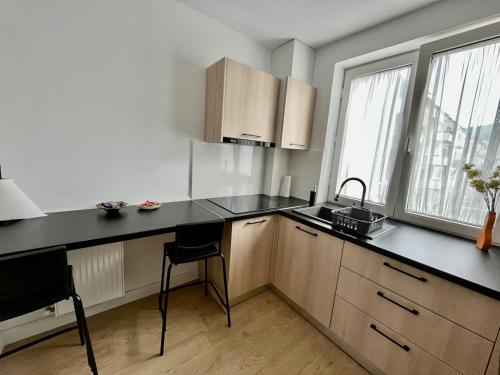 una cocina con encimera negra y algunas ventanas en Apartament Central, en Vişeu de Sus