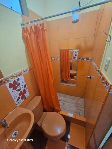 a bathroom with an orange shower curtain and a toilet at Su Majestad II in Huanta