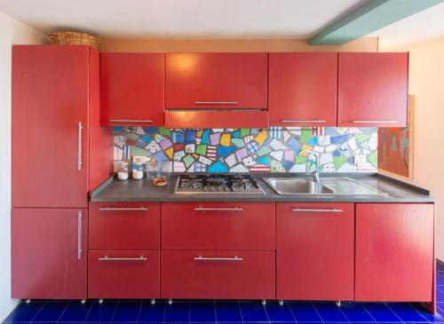 a red kitchen with a sink and red cabinets at Casa Tiberius Capri Retreat in Capri
