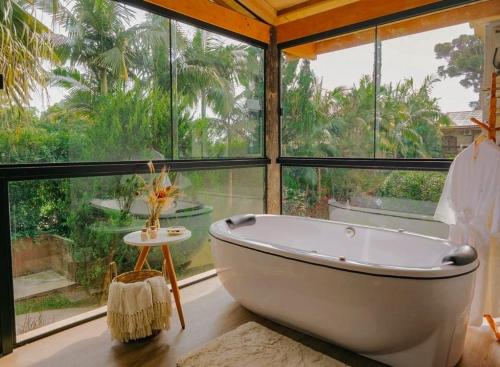 a bath tub in a room with a large window at Hotel Sonnet by Estância Santa Cruz in Curitiba