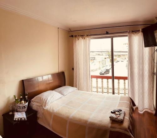 een slaapkamer met een bed en een groot raam bij ALOJAMIENTOS HOSTAL REST HOUSE in Cuenca
