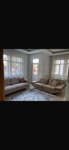 una gran sala de estar con sofás y ventanas. en MFC konaklama, en Yeşilyurt