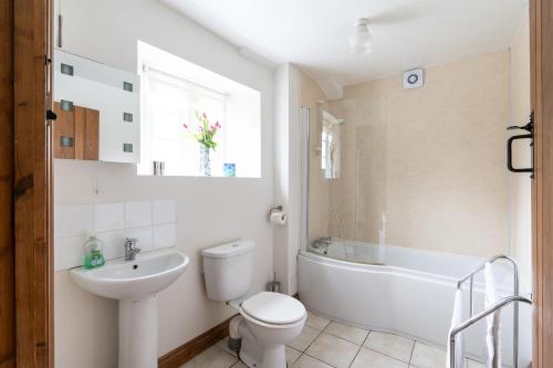 Coachmans Cottage in Loxton في Loxton: حمام ابيض مع مرحاض ومغسلة