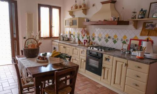uma cozinha com uma mesa e um fogão forno superior em Affittacamere Albafiorita em Castiglione dʼOrcia