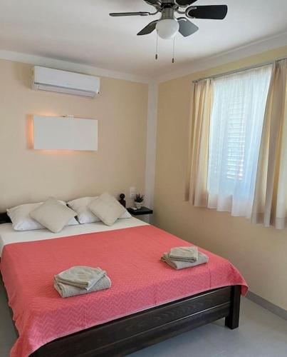a bedroom with a bed with red sheets and a ceiling fan at Apartments Vero Orebic 1 in Orebić