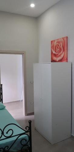 a bedroom with a white cabinet with a painting on the wall at GIOIA Holiday Home in Torre del Greco