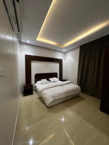 um quarto com uma cama branca e uma cabeceira em madeira em شقة بدخول ذاتي غرفتين نوم وصالة em Al-Kharj