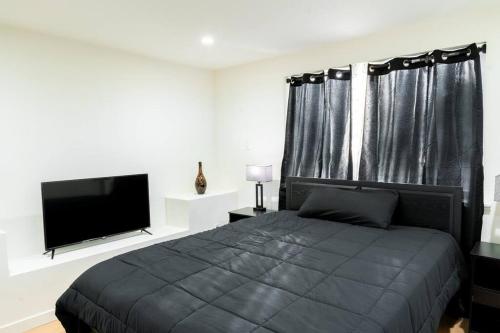 um quarto com uma cama e uma televisão de ecrã plano em Villa Palo Alto em East Palo Alto