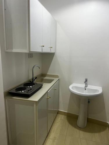 uma pequena cozinha branca com um lavatório e um lavatório em شقة بدخول ذاتي غرفتين نوم وصالة em Al-Kharj