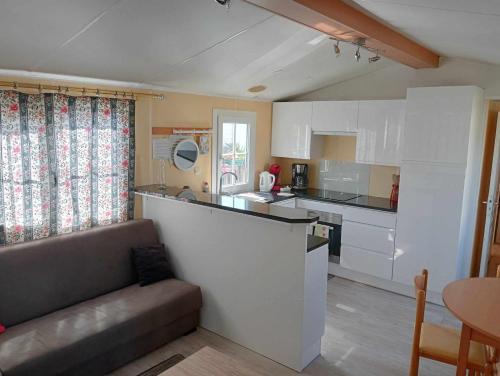 a kitchen with white cabinets and a couch in a room at Bungalow au bord de la piscine 4 pers 5A in Burinhosa