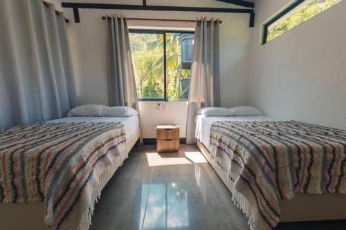 two beds in a room with a window at Casa junto al río en Bolombolo in Concordia