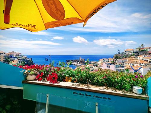 a view of the ocean from a balcony with an umbrella at ATTIC BAY - Cozy Stay with Sea View in Câmara de Lobos