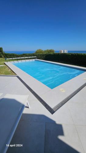 una piscina de agua azul y el océano en CASA DOMINO, SOTOGRANDE, Torreguadiaro, en Sotogrande