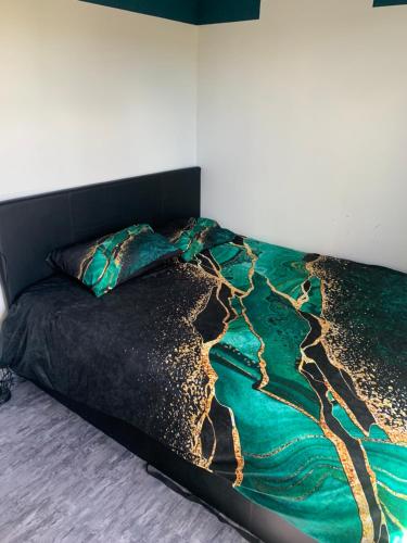 un lit avec une couette verte et noire dans l'établissement Cosy avec jardin, à Quincy-Voisins