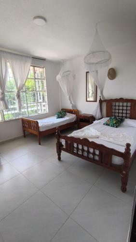 two beds in a room with two windows at FINCA VILLA MAGALY en medio de la Naturaleza in Melgar