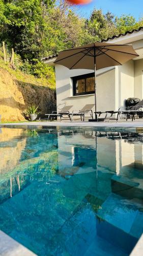 - une piscine avec un parasol et des chaises à côté dans l'établissement A CASA DI LAURENA piscine chauffée proche St Florent, à Vallecalle