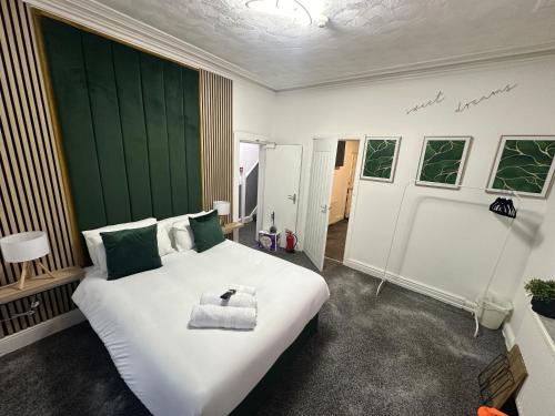 Schlafzimmer mit einem großen weißen Bett mit einem grünen Kopfteil in der Unterkunft Tropical Heaven By Luxe Holiday Accommodation in Blackpool