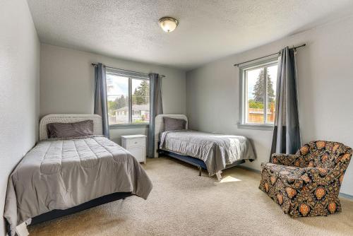 a bedroom with a bed and a chair and windows at Perfect for Families! Spokane Valley Home with Yard in Spokane Valley