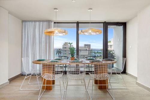 une salle à manger avec une table, des chaises et une grande fenêtre dans l'établissement HiBird- Apartment and Suites Hotel, à San Juan