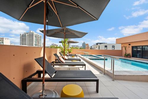 a row of lounge chairs and an umbrella on a rooftop at HiBird- Apartment and Suites Hotel in San Juan
