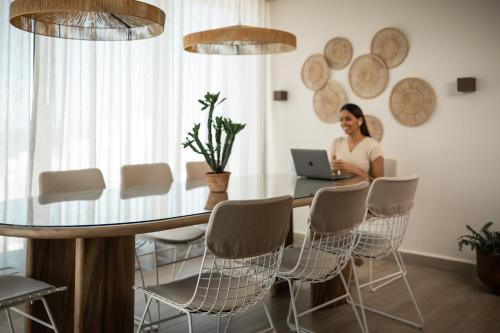 a woman sitting at a table with a laptop at HiBird- Apartment and Suites Hotel in San Juan