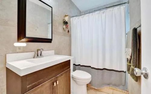 a bathroom with a sink and a toilet and a mirror at Elles Place in Fort Lauderdale