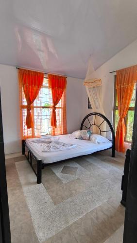 a bedroom with a large bed with orange curtains at FINCA VILLA MAGALY en medio de la Naturaleza in Melgar