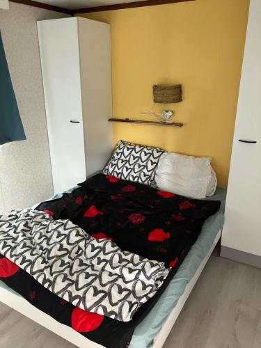 a bed with a black and white comforter on it at Beach house in Zandvoort