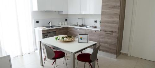 a kitchen with a white table and red chairs at Residenza Verona New Life in Castel d'Azzano