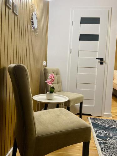 a room with a table and chairs and a table with a vase of flowers at DOBA RENT Wysockiego 104 in Białystok