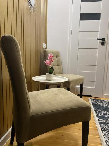 a room with a table and a chair and a table with flowers at DOBA RENT Wysockiego 104 in Białystok