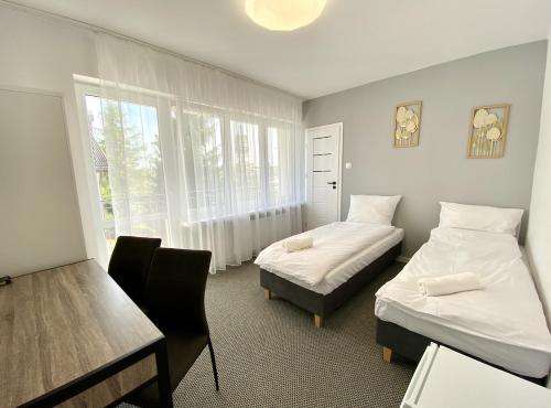 a room with two beds and a desk and a table at DOBA RENT Wysockiego 104 in Białystok