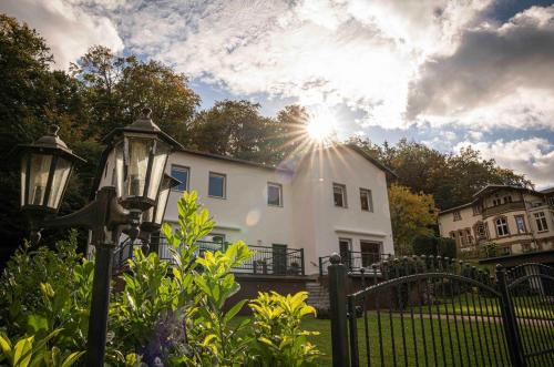 una casa blanca con el sol detrás de una valla en Seeblick, en Stuer
