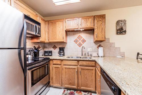 a kitchen with wooden cabinets and a stainless steel refrigerator at Cimarron 404 by Great Western Lodging in Breckenridge