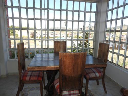 una mesa de madera y sillas en una habitación con ventanas en SORACA MANTO REAL, en Soracá